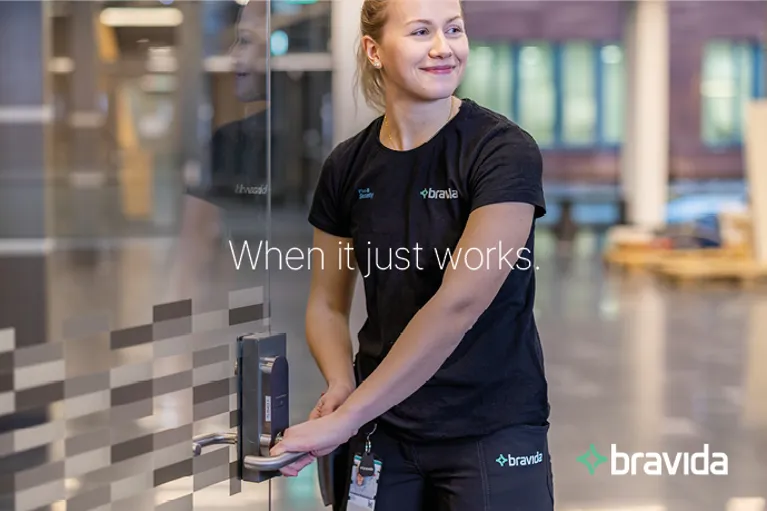 Woman in Bravida profile clothing opens a door with an electronic lock. Text: "When it just works." and Bravida logo