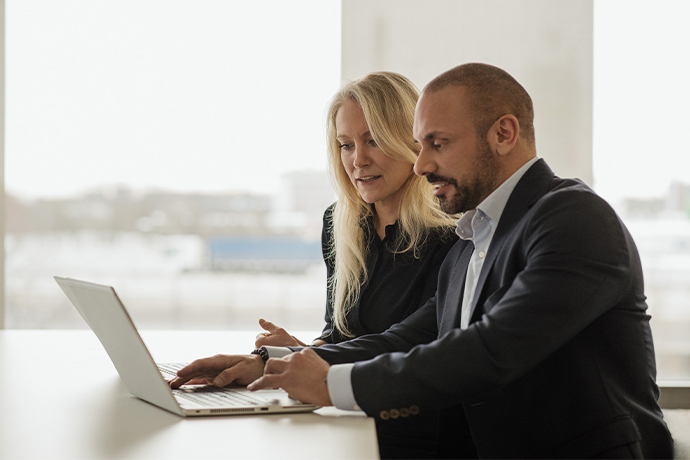 En man och en kvinna vid en dator på ett kontor