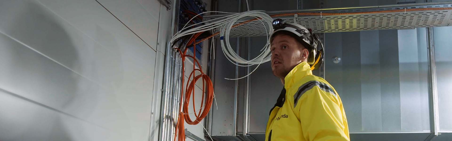 Bilden föreställer en elektriker på en byggarbetsplats