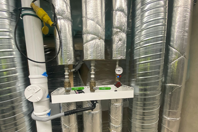 Ventilations- och rörinstallation med injusteringsventiler i teknikutrymme.