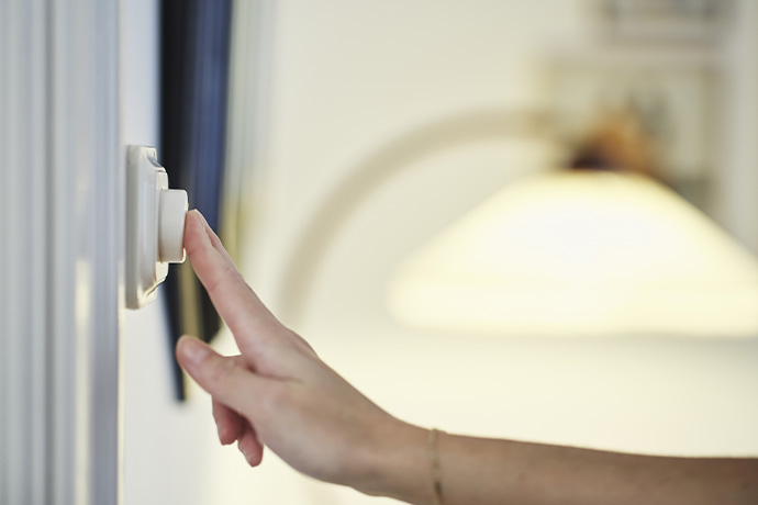 Bilden visar en person som trycker på en lysknapp