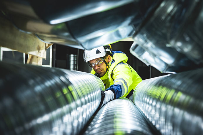 Bilden visar en tekniker och vetilationsrör