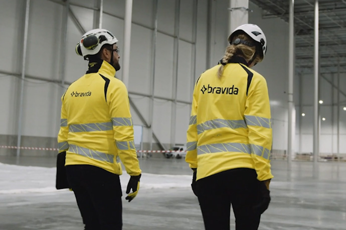 Två tekniker med varselkläder och hjälmar på en byggarbetsplats
