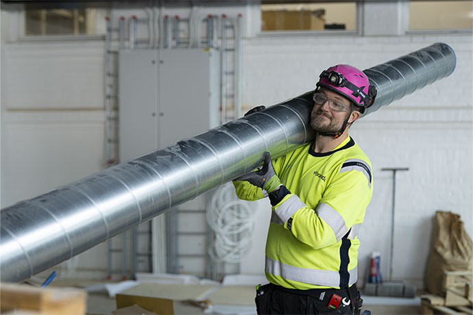 En ventilationstekniker som bär på ett ventilationsrör