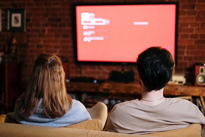 Två personer i en soffa som ser på tv