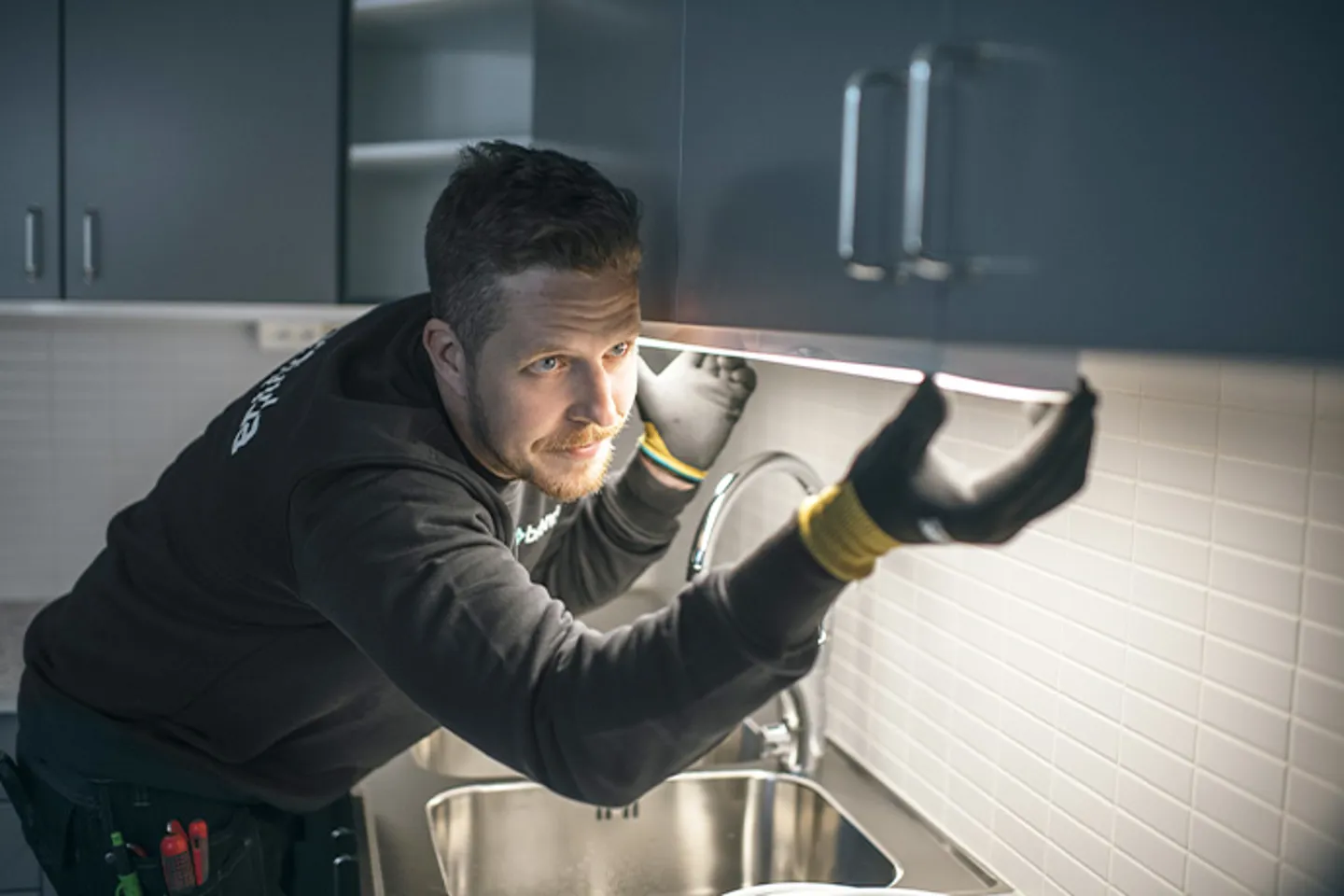 Bilden visare en servicetekniker som byter lysrör i ett kök