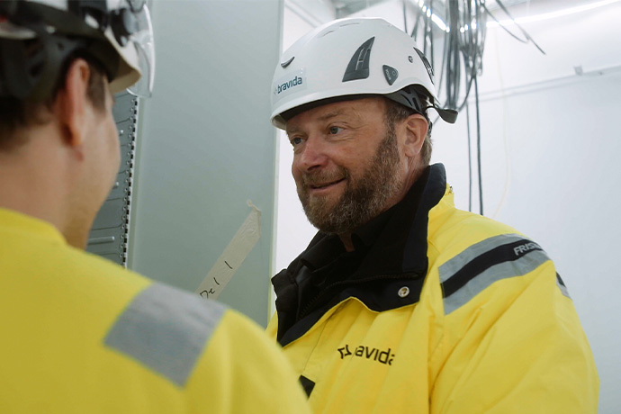 Två tekniker i varselkläder och hjälmar på en byggarbetsplats