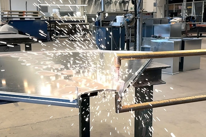 Bilden visar en plåt som svetsas i en industriell miljö